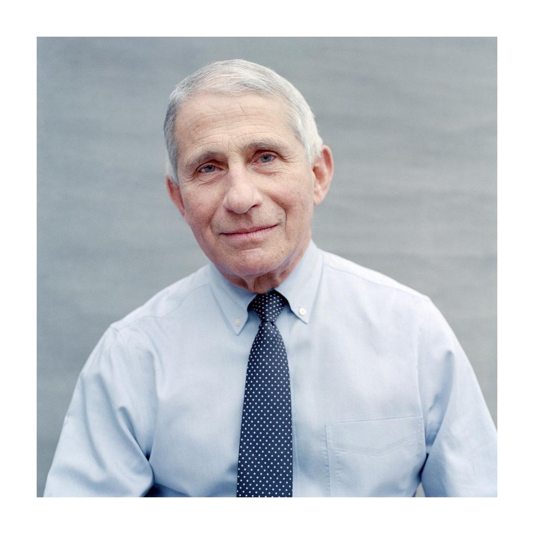 Portrait of Anthony Fauci wearing a light blue dress shirt and polka dot tie against a plain grey background