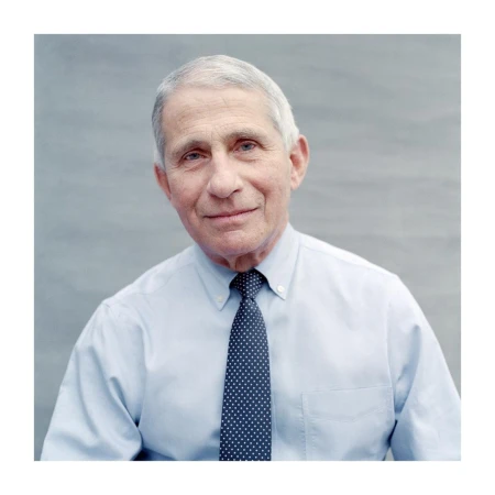 Portrait of Anthony Fauci wearing a light blue dress shirt and polka dot tie against a plain grey background