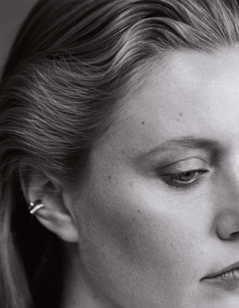 Close-up monochrome portrait of a woman with slicked-back hair and ear cuffs photographed by Jody Rogac.