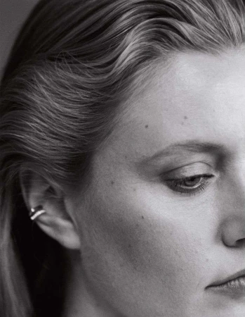 Close-up monochrome portrait of a woman with slicked-back hair and ear cuffs photographed by Jody Rogac.