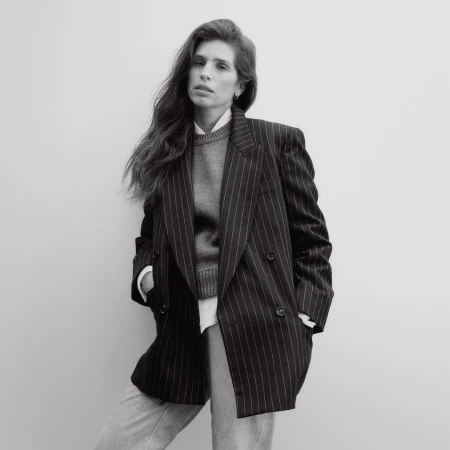 Portrait of a woman wearing a pinstripe blazer and knit sweater against a plain white background by Jody Rogac.
