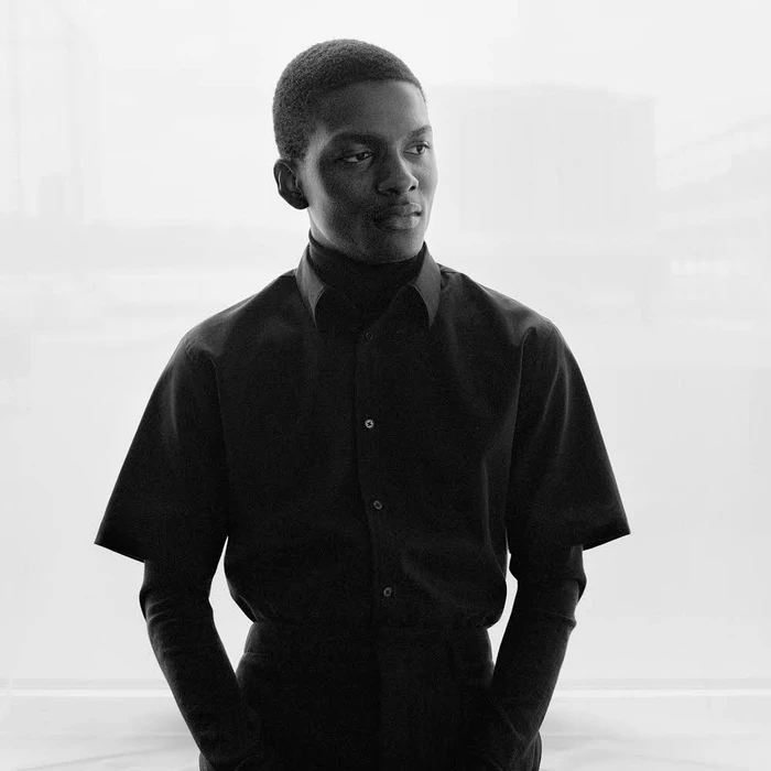 Portrait of a Black man in a dark short-sleeve shirt against a bright background by Jody Rogac