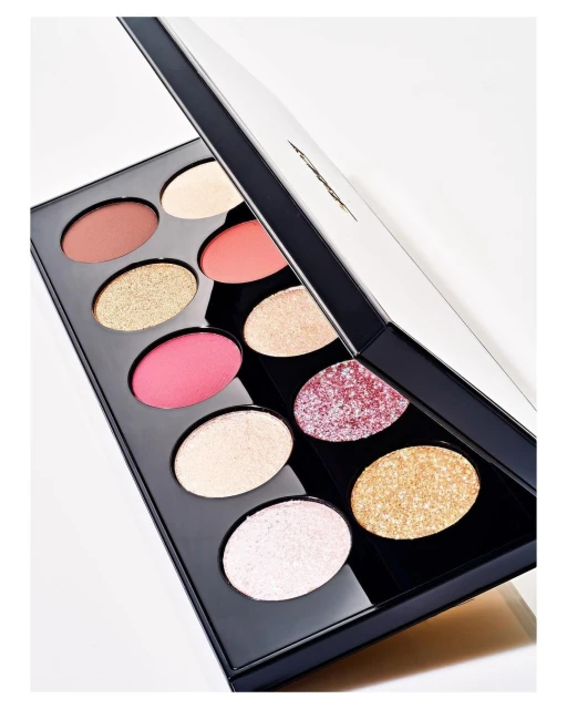 Eye shadow palette featuring a variety of colors including pink, gold, and bronze hues with a glossy black case and white background.