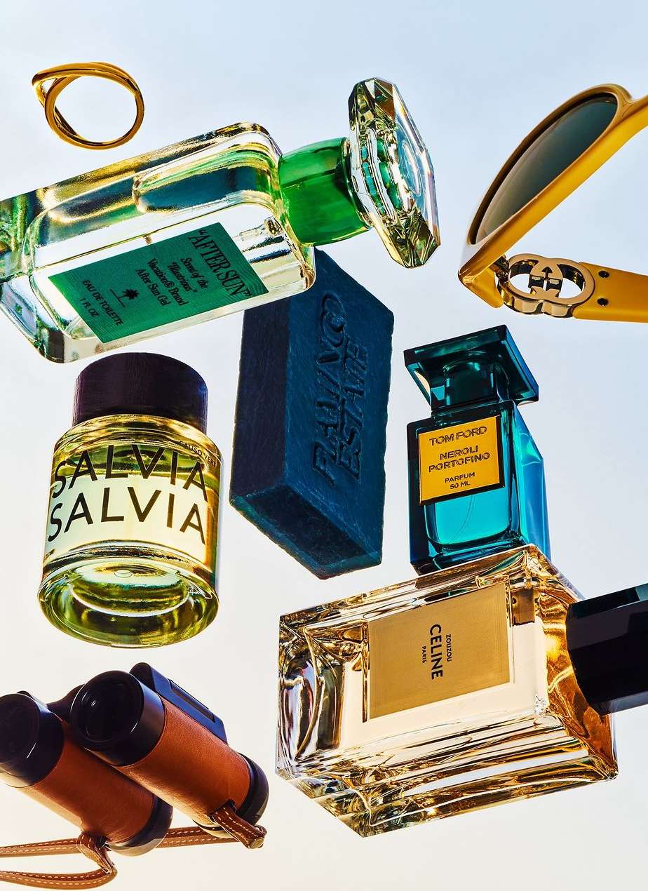 Still life featuring perfume bottles from Tom Ford, Celine, and other luxury brands, along with sunglasses, soap, a ring, and binoculars.