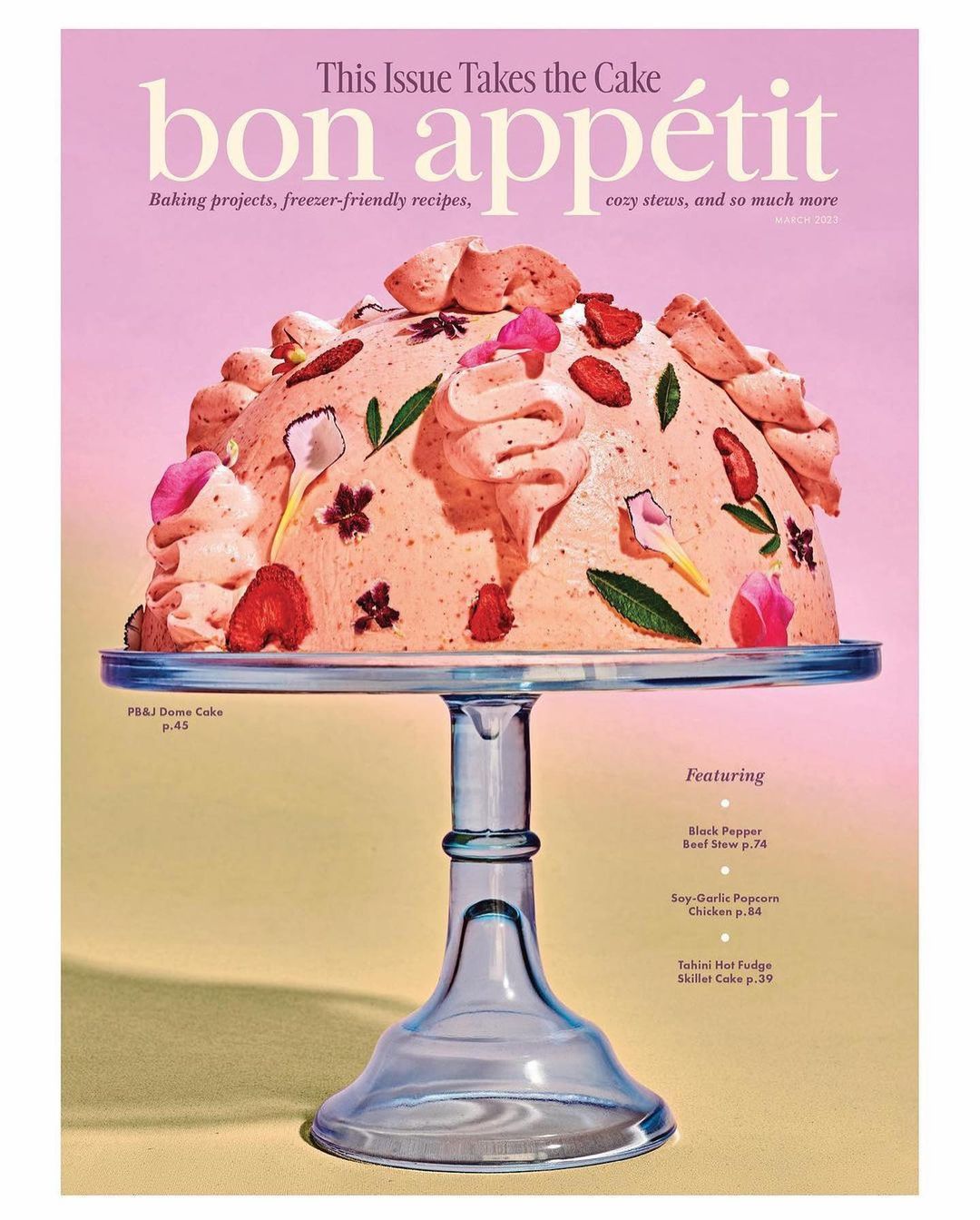 Magazine cover featuring a cake decorated with frosting, strawberries, and flowers on a blue glass cake stand against a pink background.