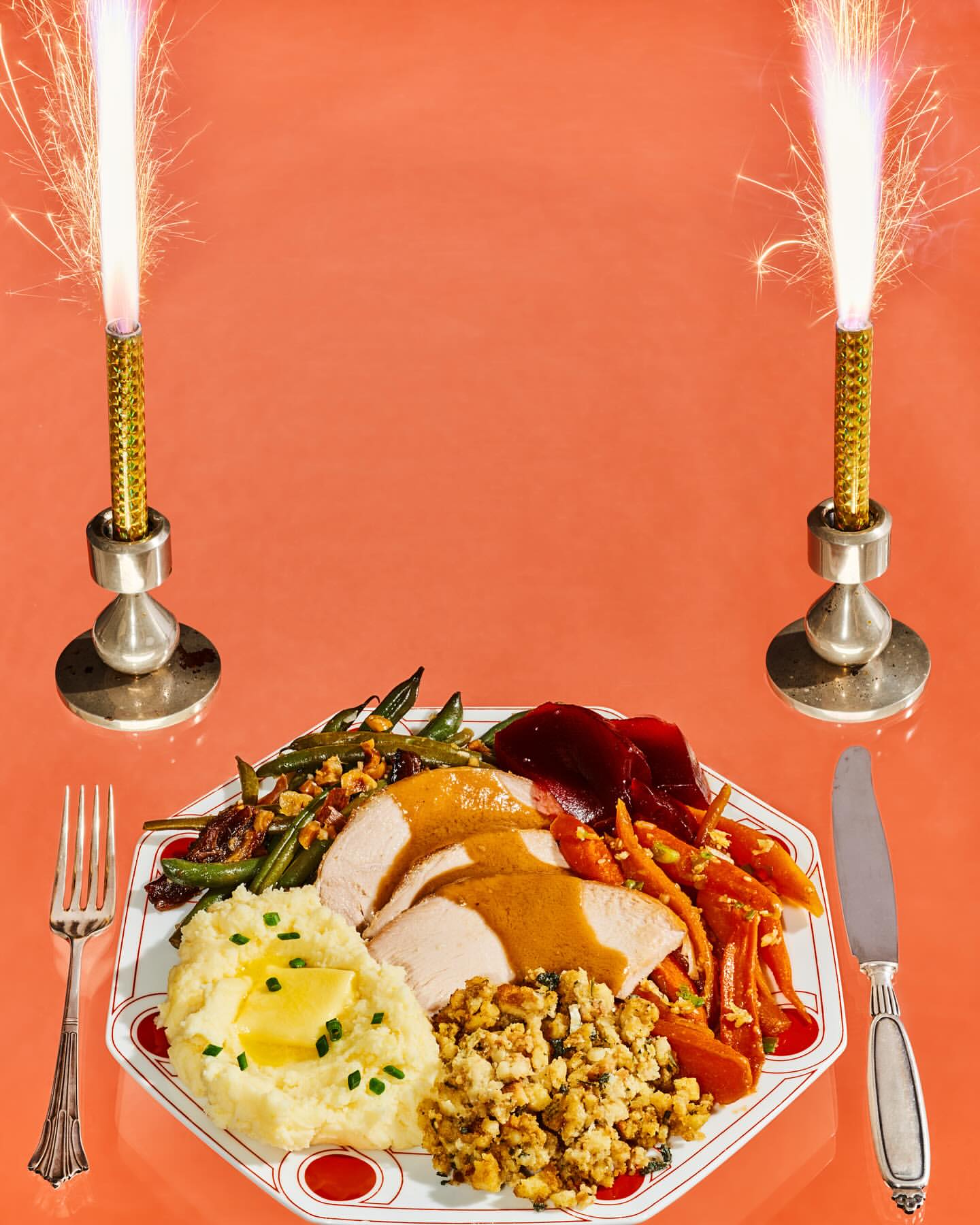 Celebratory Thanksgiving dinner on a white plate with sides of potatoes, stuffing, green beans, carrots, and cranberry sauce, sparkler candles.