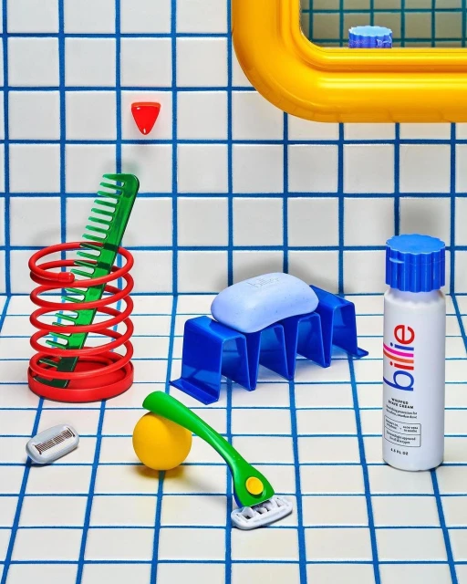 Still life of bathroom objects including soap, razor, comb, bottle, and holder arranged on a tiled surface with blue lines.