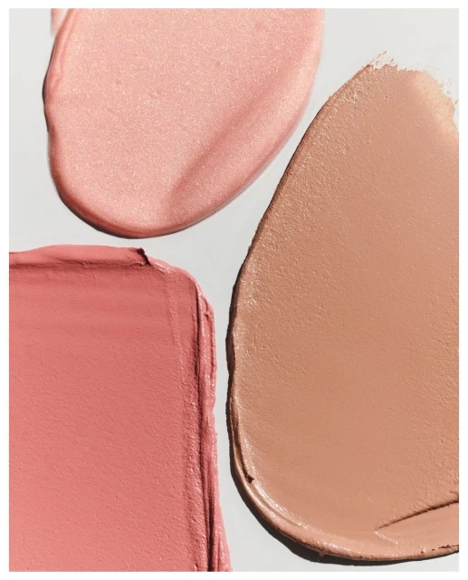 Close-up of three cream makeup swatches in pink and tan hues against a white background, suitable for beauty and cosmetics promotions.