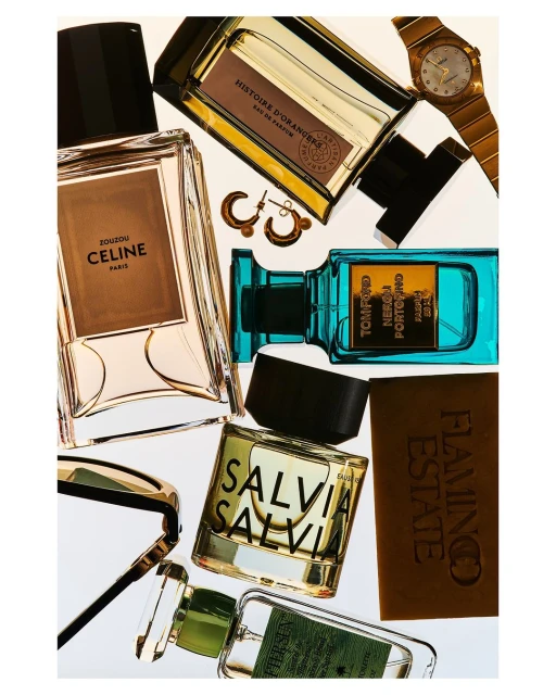 Overhead shot of curated collection of fragrance bottles including Tom Ford, Celine, and Histoire D'Orangers, along with gold watch and earrings.
