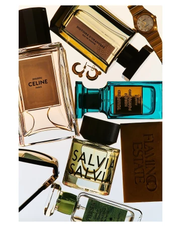Overhead shot of curated collection of fragrance bottles including Tom Ford, Celine, and Histoire D'Orangers, along with gold watch and earrings.
