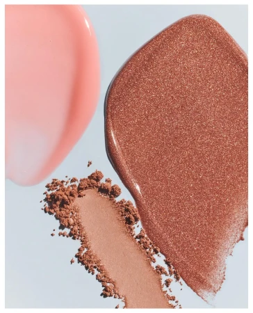 Cosmetic product swatches: glossy pink lip gloss, shimmery bronze highlighter, and neutral blush on a light blue background.