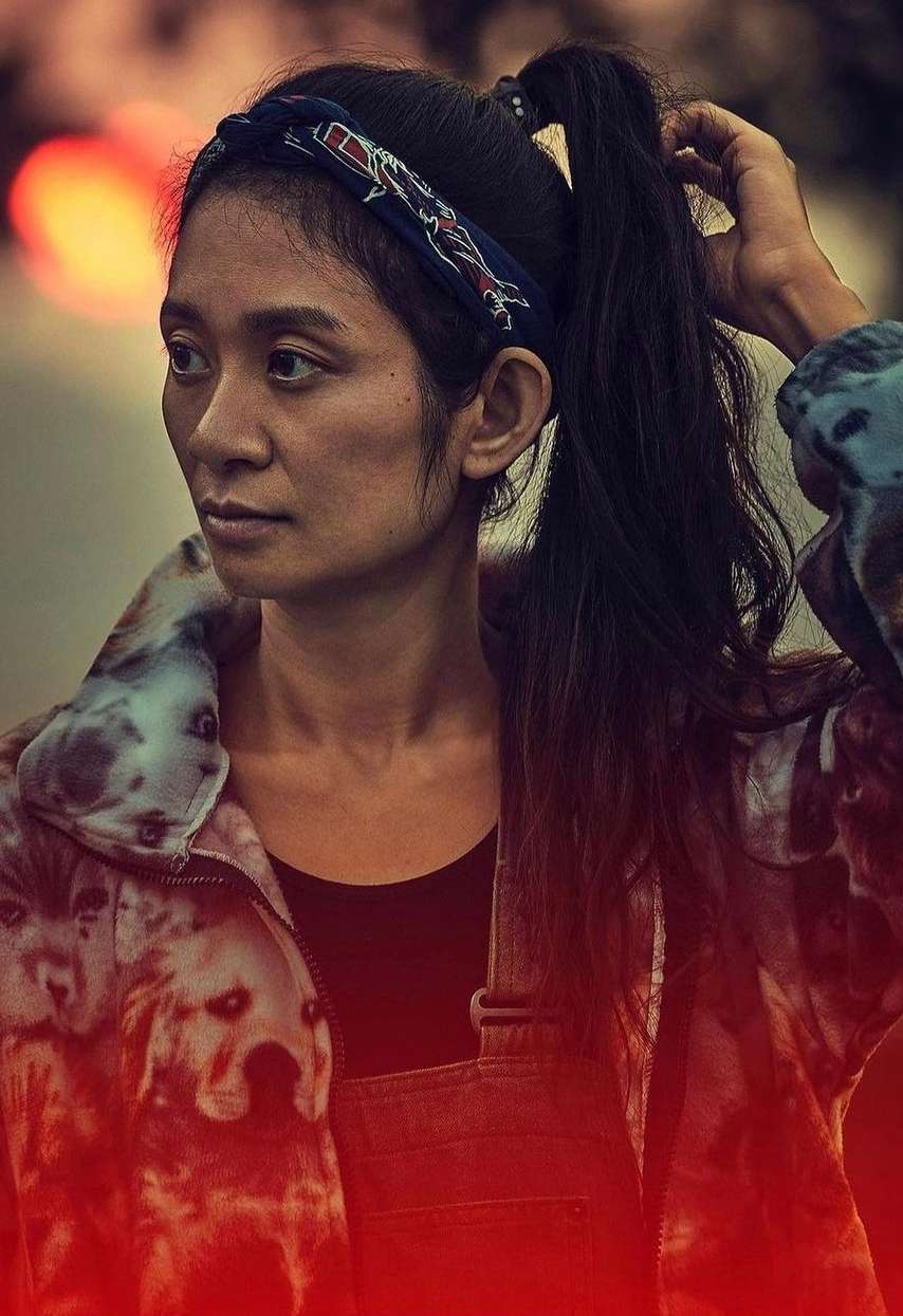 Portrait of an adult female with a patterned headband and jacket, looking to the side in a dimly lit outdoor environment.