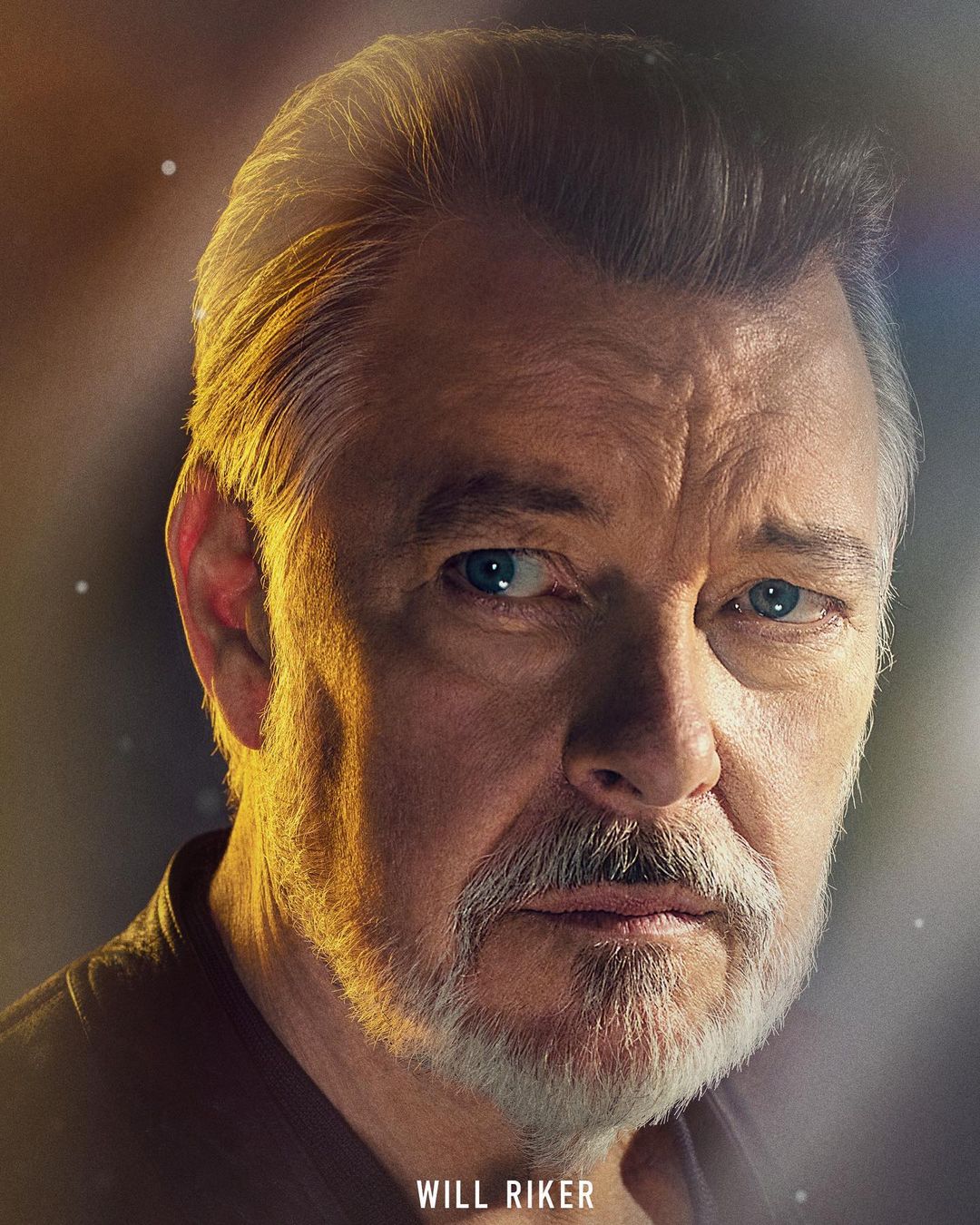 Close-up portrait of a mature adult male with graying hair and beard, looking directly at the viewer with a serious expression.