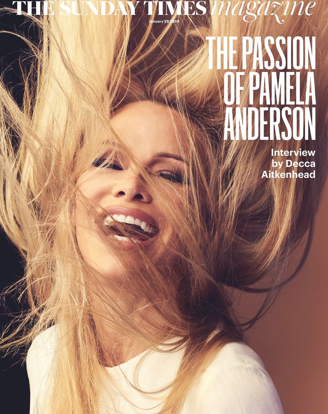 Magazine cover featuring Pamela Anderson, blonde hair styled upwards, smiling, wearing a white top against black and peach background.
