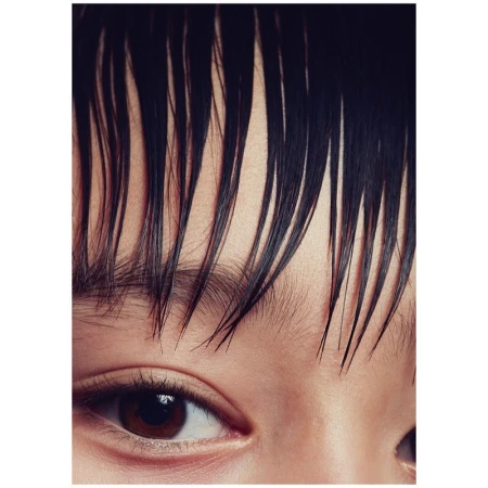 Close-up portrait framing a person's eye and wet, dark hair strands falling across the forehead.