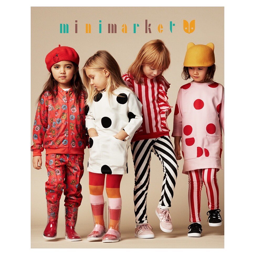 Four young children stand in a studio wearing colorful patterned outfits and rain boots promoting the Minimarket brand.