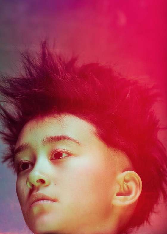 Portrait of a young person with spiky dark hair against a colorful gradient background; close-up on their face; artistic lighting.