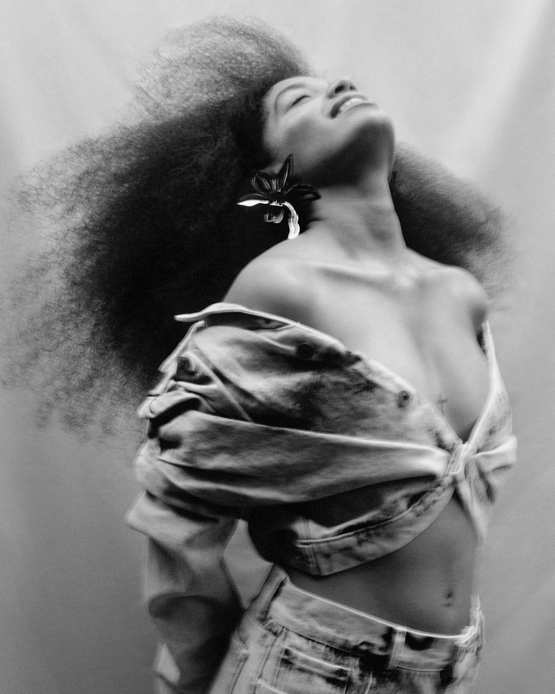 Black and white portrait of an adult woman with curly hair and a denim outfit, captured in a photo studio setting with soft lighting.