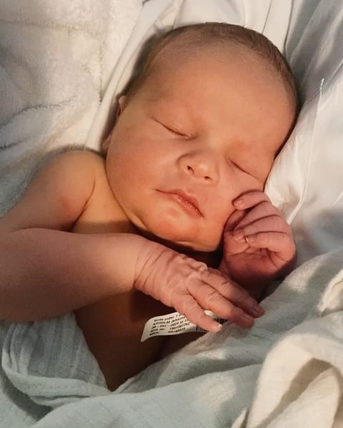 Close-up of a newborn baby sleeping peacefully on a white blanket, showcasing the infant's serene expression and delicate features.