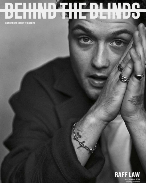 Black and white portrait of Raff Law on Surrender magazine cover, issue 12, with hands near face, rings, and bracelet.