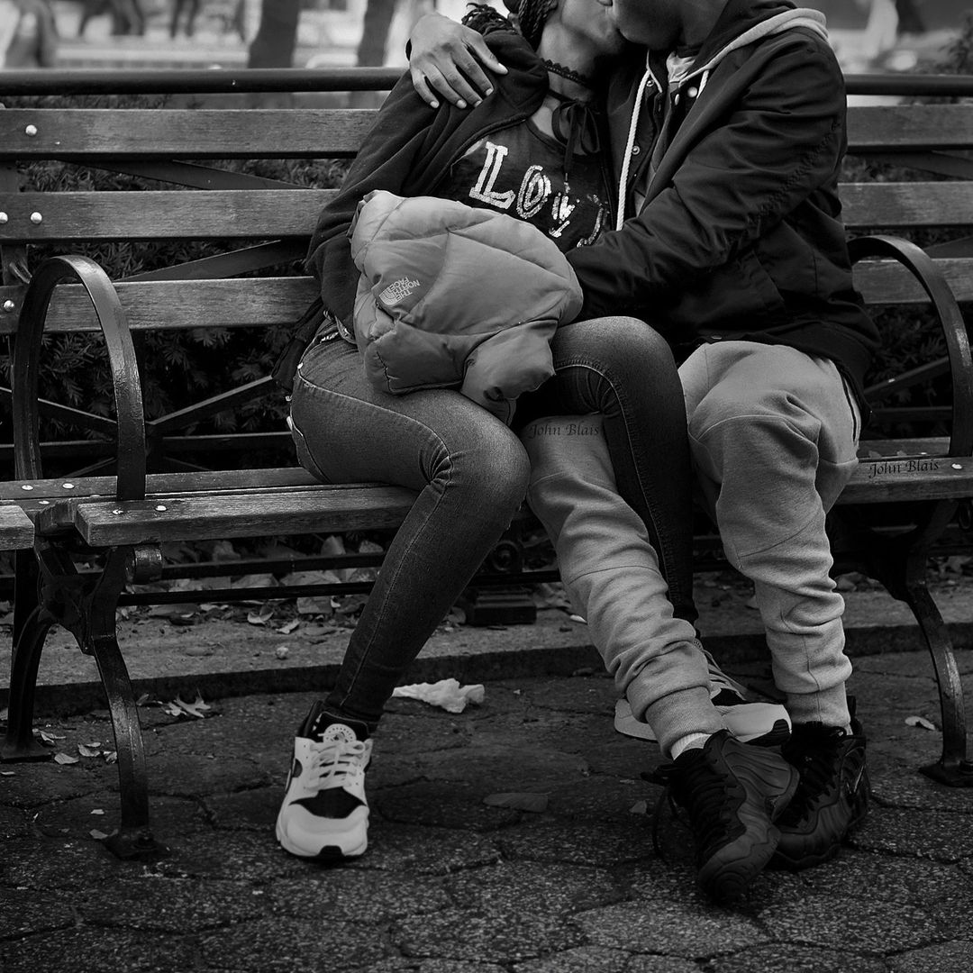 Black and white portrait of a couple embracing on a wooden park bench in Chicago, photographed by John Blais.