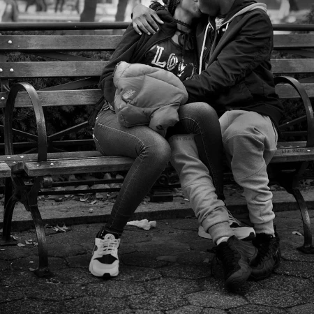 Black and white portrait of a couple embracing on a wooden park bench in Chicago, photographed by John Blais.