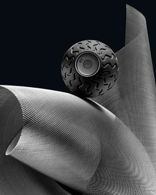A textured ball with a speaker-like center sits atop a curved, dotted material against a dark background, creating a modern product still life.
