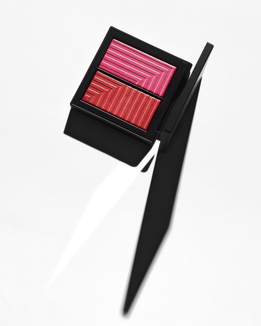 Dual blush palette in black compact case featuring red and pink powder, studio shot for beauty and cosmetic advertising.