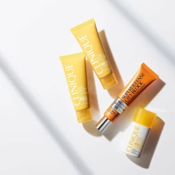Four Clinique skincare tubes arranged diagonally on a clean white surface with soft directional shadows casting across the frame