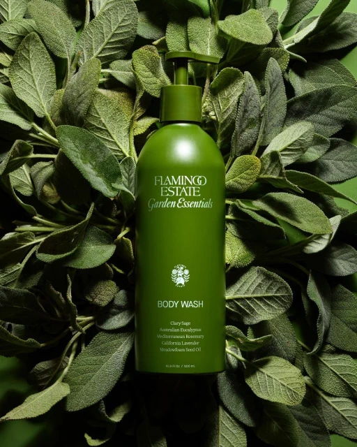Green Flamingo Estate body wash bottle centered among lush green leaves, product shot, beauty and personal care. Garden Essentials.