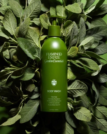 Green Flamingo Estate body wash bottle centered among lush green leaves, product shot, beauty and personal care. Garden Essentials.