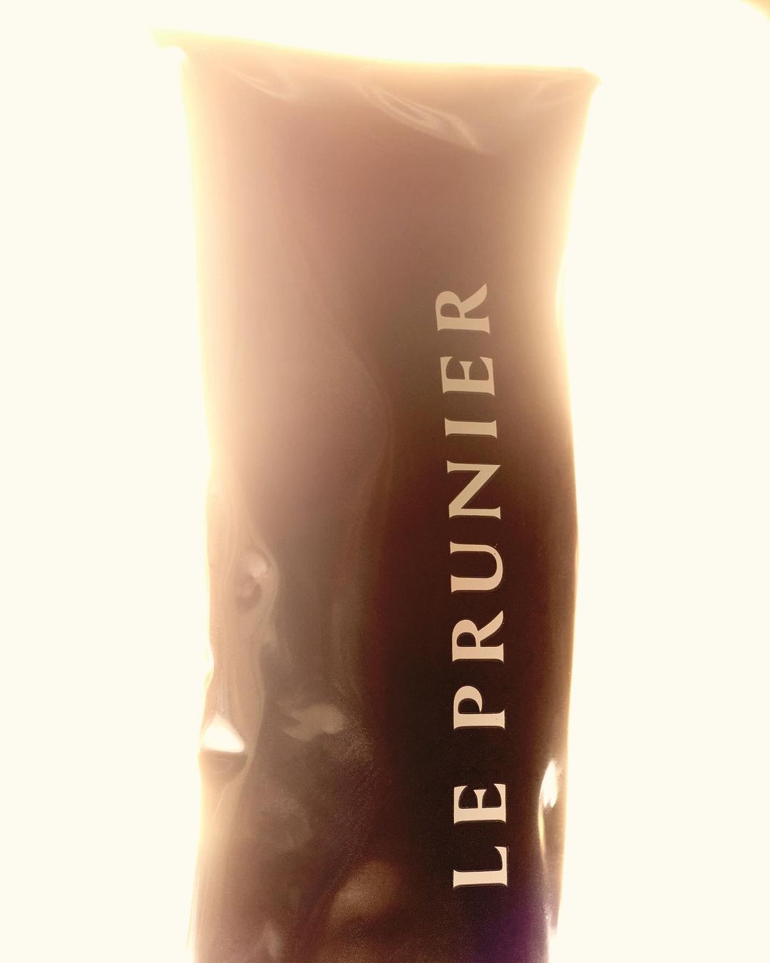 Dark brown bottle of LE PRUNIER skincare product. White lettering on the container is the brand's name.