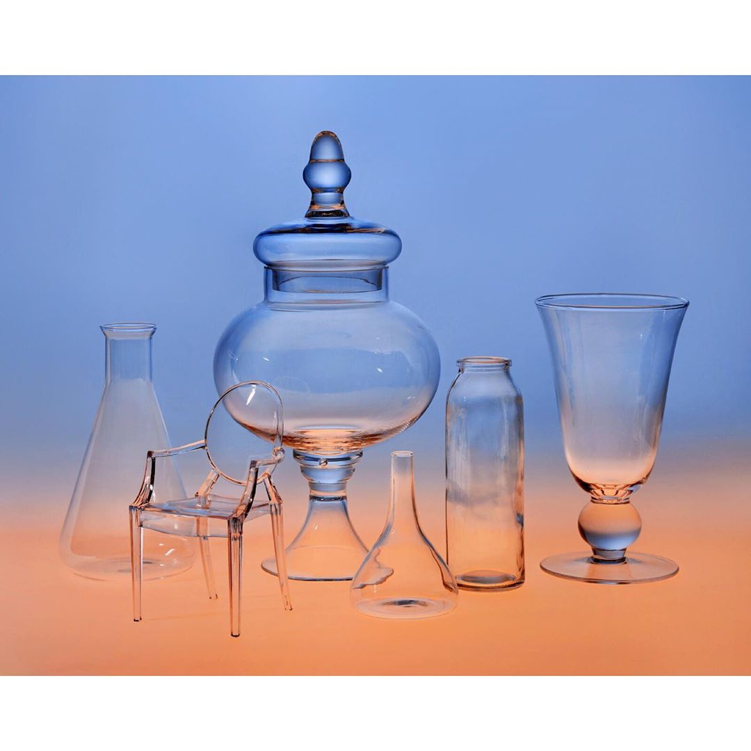 Arrangement of transparent objects: a large lidded jar, Erlenmeyer flask, funnel, glass bottle, wine glass, and a miniature chair.