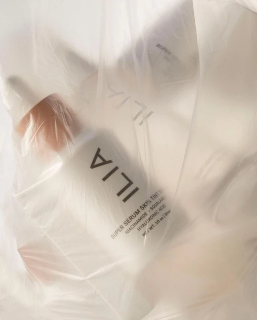 Ilia Super Serum Skin Tint bottles in a translucent plastic bag, showcasing minimalist packaging and the beauty industry's focus on skincare.