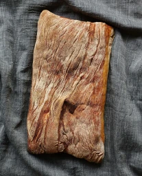 Top-down view of a rectangular artisanal loaf of bread resting on dark grey textured fabric