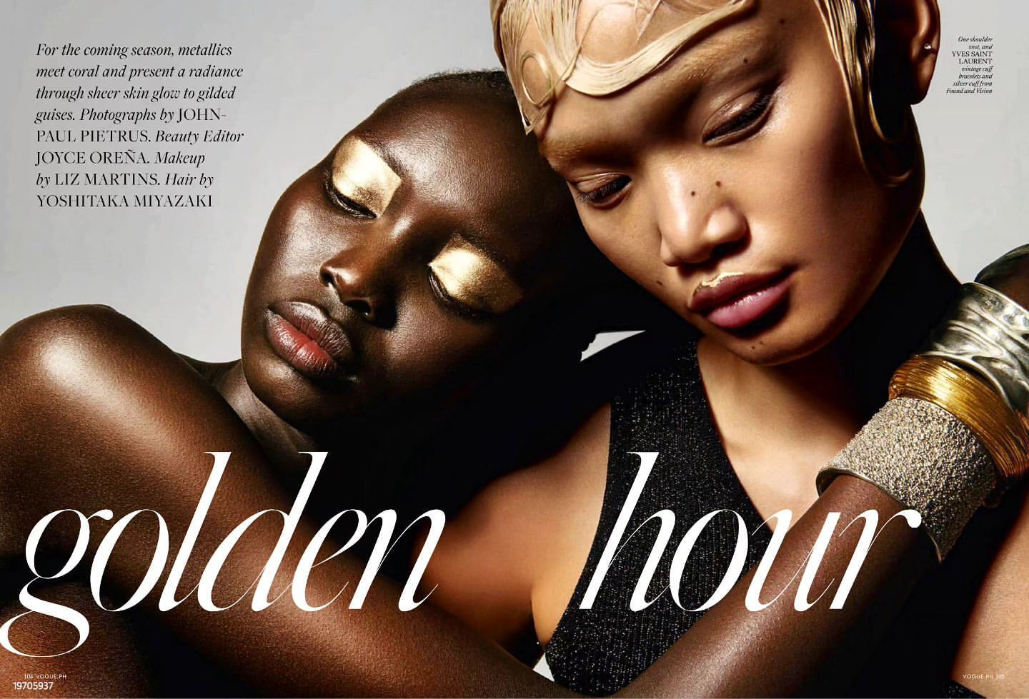 Two female fashion models with gold eye makeup and jewelry posing closely together in a studio, creating a radiant and luxurious look.