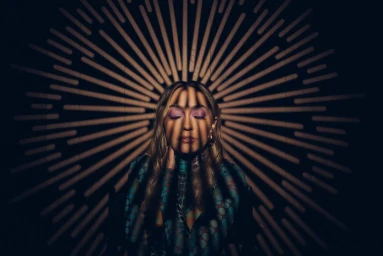 Close-up portrait of a woman with closed eyes and patterned top against a radial shadow pattern backdrop