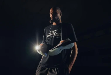 Kevin Durant holding sneakers over his shoulder in a low key studio portrait by Johnnie Izquierdo