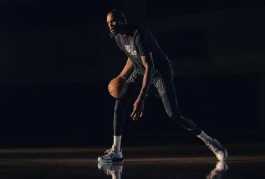 Basketball player dribbling a basketball on a dark court under directional lighting by Johnnie Izquierdo