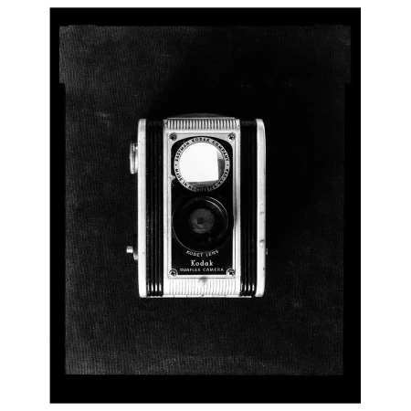 Vintage Kodak Brownie camera in black and white, featuring a boxy design, reflective lens, and classic Kodak branding, on a dark background.