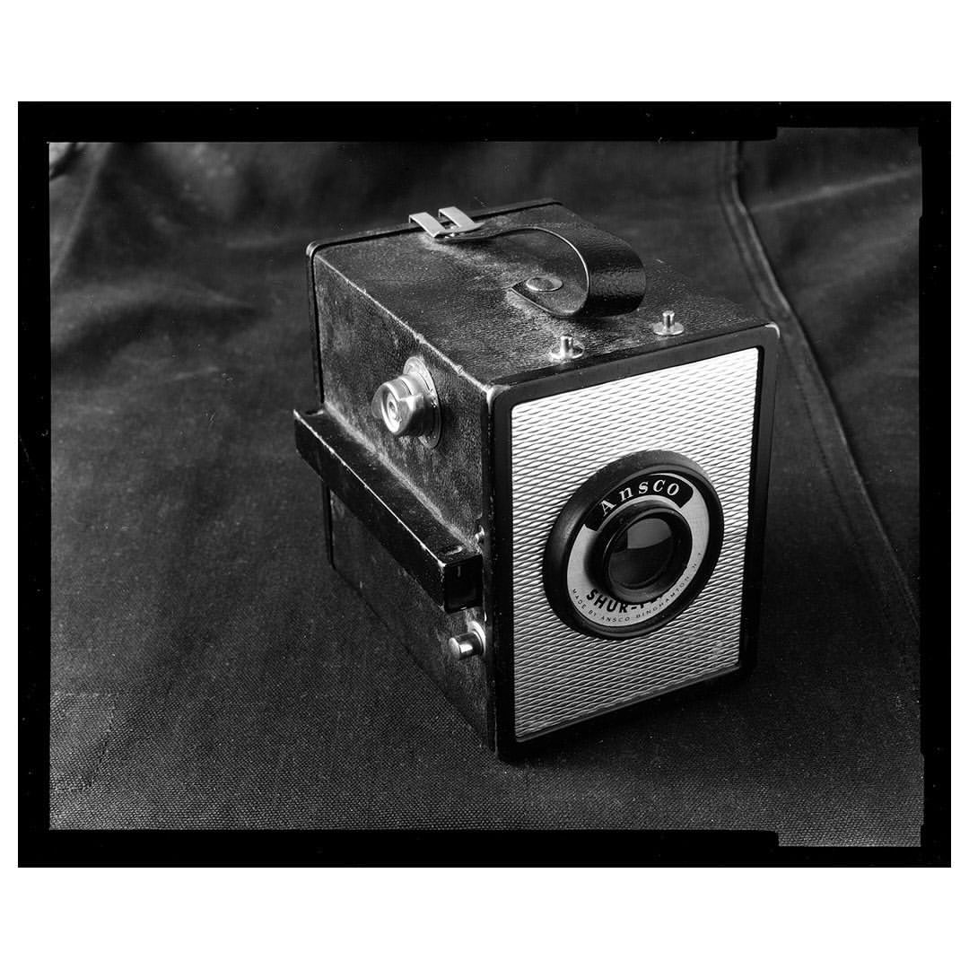 Vintage Ansco Shur-Shot box camera in black and white, featuring the Ansco logo and a textured background.