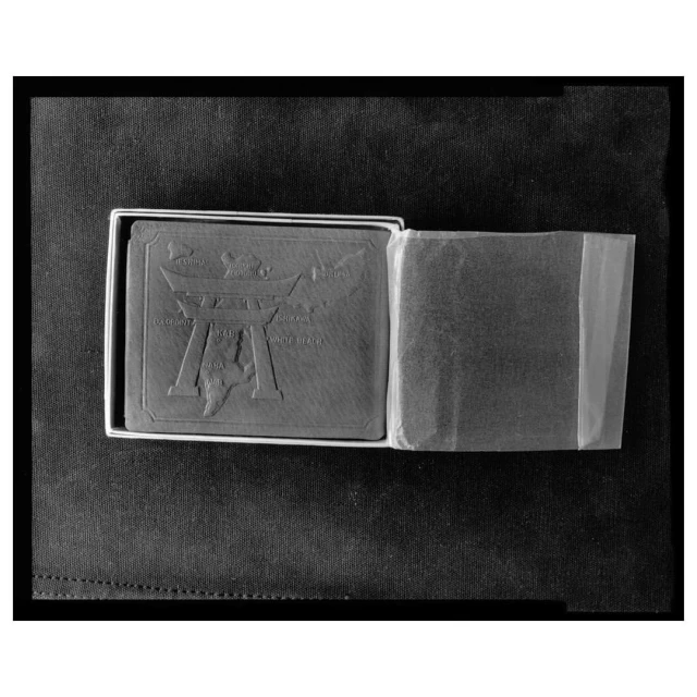 Box of cards features an embossed design with a stylized torii gate and text in monochrome, presented on a dark, textured surface.