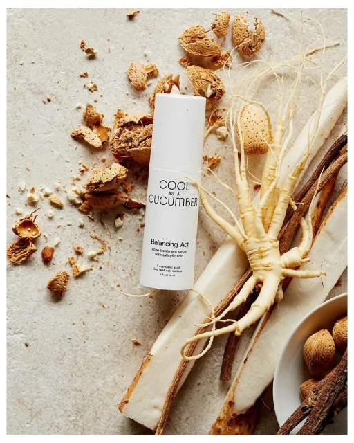 Close-up shot of a white skincare bottle surrounded by almonds and natural elements on a textured surface, highlighting beauty and wellness.