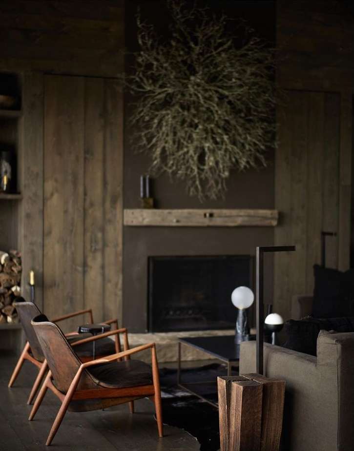 Cozy living room interior featuring mid-century modern chairs, fireplace, and rustic wood accents creating a warm, inviting space.