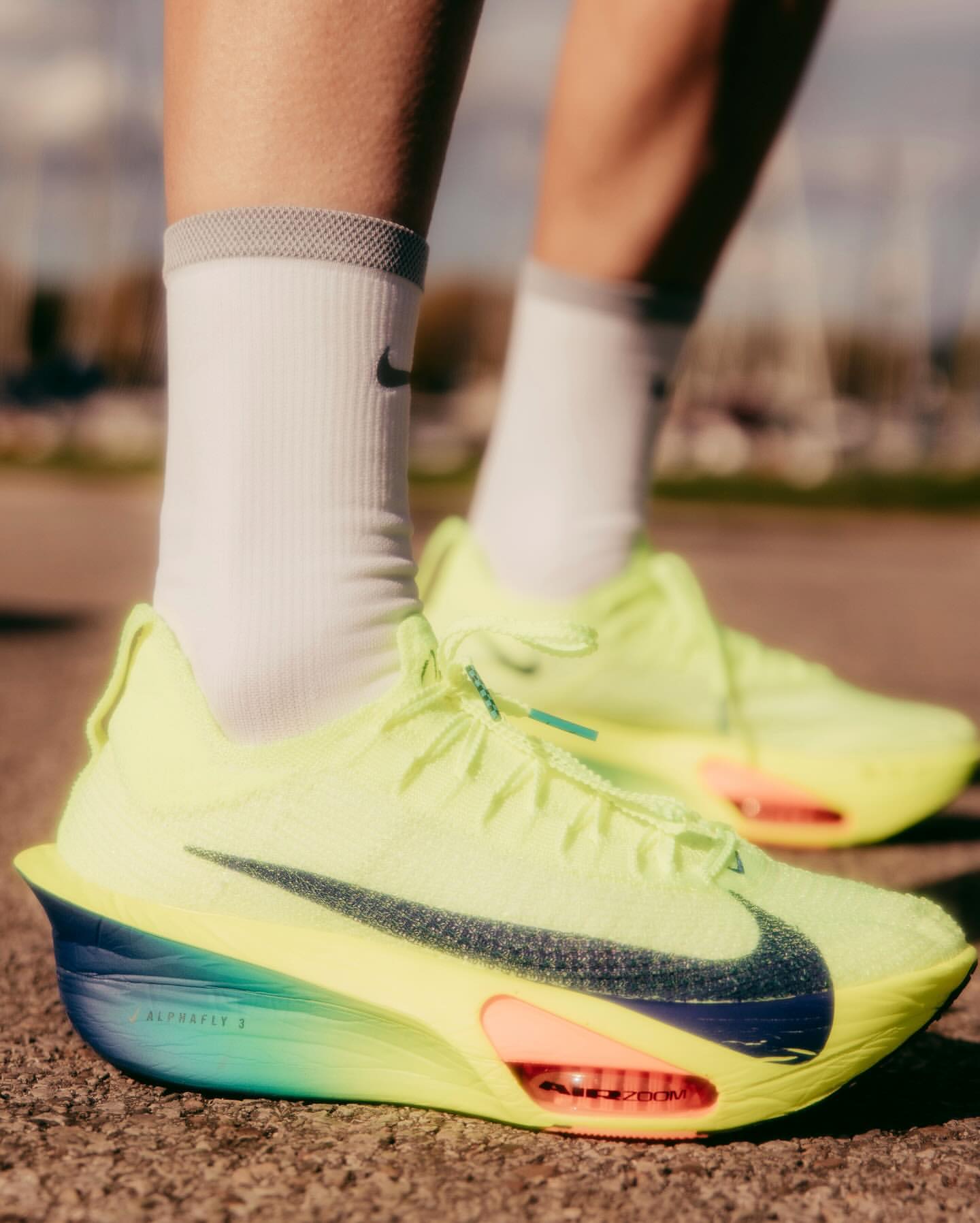 Close-up shot of neon yellow Nike running shoes with white socks and a blurred background, highlighting athletic footwear and active lifestyle.