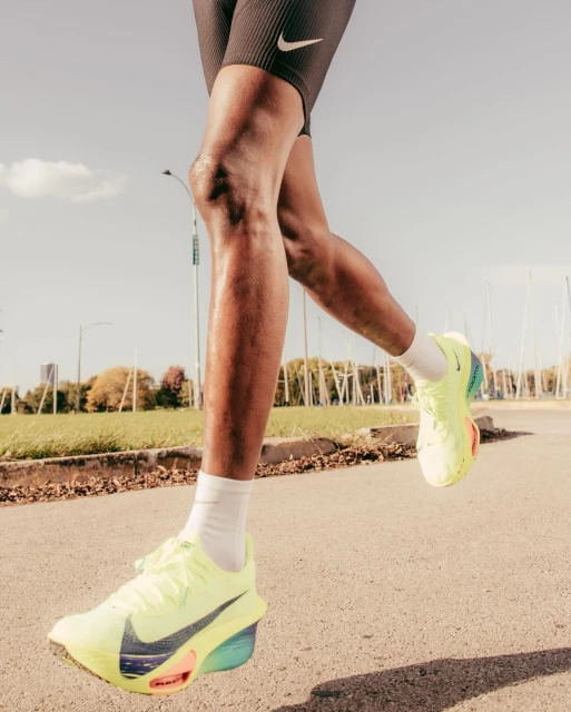 Close-up of a Black male athlete in Nike running shoes and shorts on a city street, emphasizing fitness, sport, and athletic apparel.