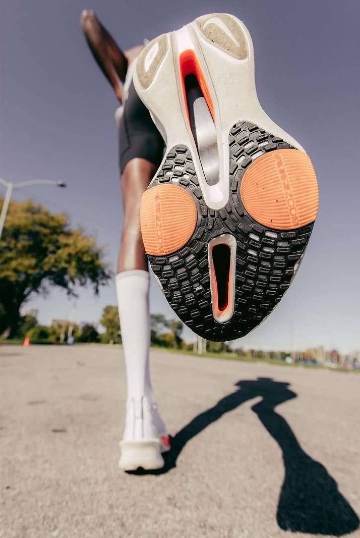 Close-up of a runner's sneaker sole in motion, emphasizing the design and technology for sports and fitness performance on a sunny day.