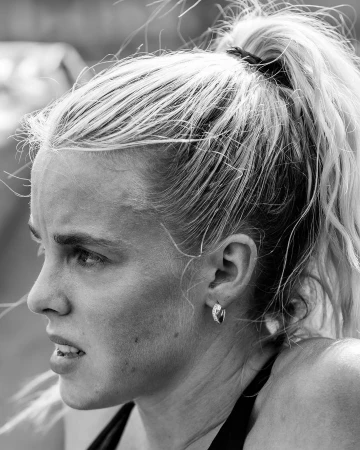Close-up monochrome portrait of a woman with her hair in a high ponytail wearing hoop earrings.