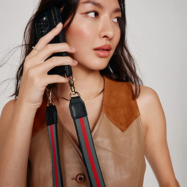 Portrait of an Asian woman wearing a sleeveless dress and holding a cell phone with a black case and colorful strap.