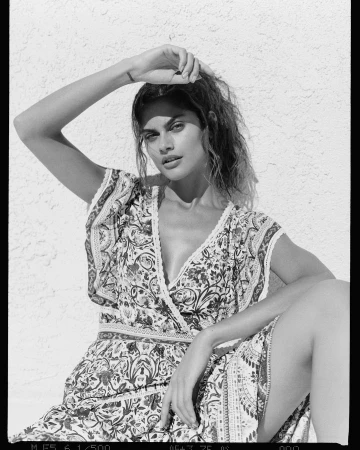Black and white portrait of a woman in a patterned dress posing against a textured stucco wall in Los Angeles.